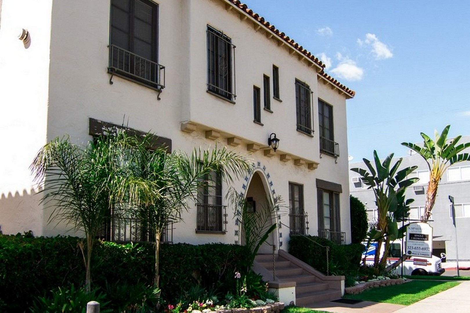 A white house with a black balcony and a black railing.